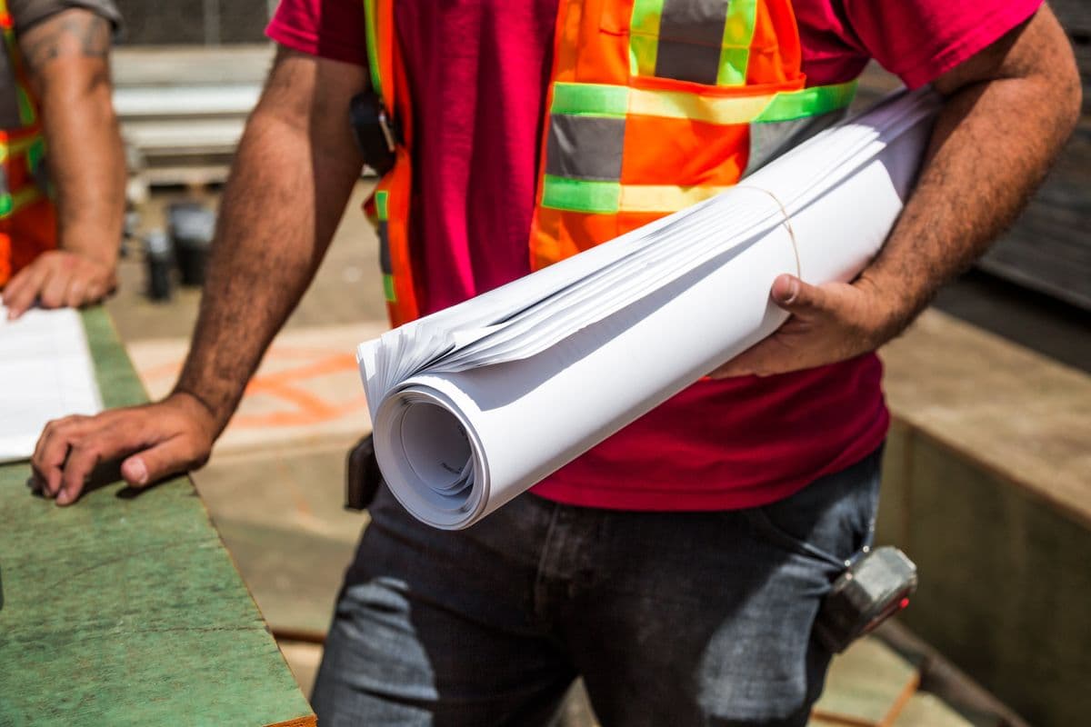Construction worker reviewing blueprints on site